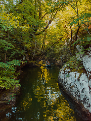 Image showing A young couple enjoying an idyllic kayak ride in the middle of a beautiful river surrounded by forest greenery