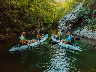 Image showing A group of friends enjoying having fun and kayaking while exploring the calm river, surrounding forest and large natural river canyons