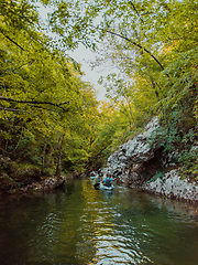 Image showing A group of friends enjoying having fun and kayaking while exploring the calm river, surrounding forest and large natural river canyons