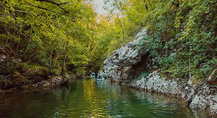 Image showing A group of friends enjoying having fun and kayaking while exploring the calm river, surrounding forest and large natural river canyons