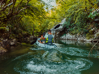 Image showing A young couple enjoying an idyllic kayak ride in the middle of a beautiful river surrounded by forest greenery