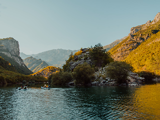 Image showing A group of friends enjoying having fun and kayaking while exploring the calm river, surrounding forest and large natural river canyons