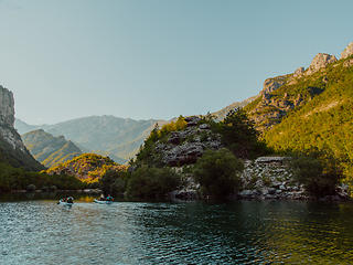 Image showing A group of friends enjoying having fun and kayaking while exploring the calm river, surrounding forest and large natural river canyons