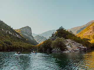 Image showing A group of friends enjoying having fun and kayaking while exploring the calm river, surrounding forest and large natural river canyons