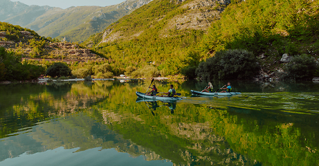 Image showing A group of friends enjoying having fun and kayaking while exploring the calm river, surrounding forest and large natural river canyons