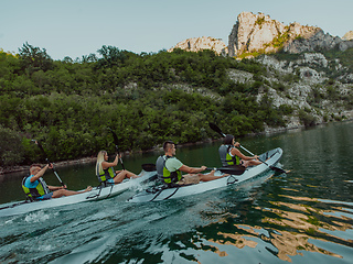 Image showing A group of friends enjoying having fun and kayaking while exploring the calm river, surrounding forest and large natural river canyons