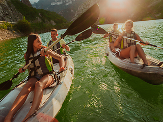 Image showing A group of friends enjoying fun and kayaking exploring the calm river, surrounding forest and large natural river canyons during an idyllic sunset.