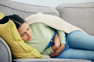 Image showing Stomach pain, pms and woman on a sofa with stress, bad or gut health, gas or ibs in her home. Abdomen, anxiety and female person in living room with gas, digestion or constipation from endometriosis