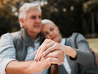 Image showing Holding hands, couple and a cane in nature for love, bonding and support. Peace, closeup and a senior man and woman in a park with a walking stick, care and together in a garden with a hug on a date