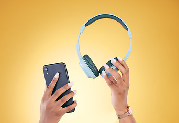 Image showing Hands, phone and headphones for music on a yellow background in studio for a streaming subscription service. Mobile, internet and radio with a person listening to audio through an entertainment app