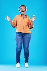 Image showing Black woman, headphones and singing to music with dance in a studio. Audio streaming, radio and happy female person with blue background and excited from celebration and freedom with hip hop song