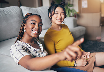 Image showing Pointing, friends and women in home for visit, bonding and conversation in living room together. Hand gesture, showing house decor and black female and Asian person in lounge to relax on weekend