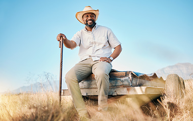 Image showing Happy, African farmer and portrait in the countryside and man, sitting and watching over environment, field and land. Farming, meadow and agriculture worker outdoor with smile or happiness in summer