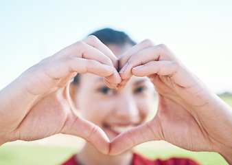 Image showing Heart shape, closeup and hands of woman with a care, sweet and cute gesture outdoor on a field. Happy, smile and zoom of a young female person with a love sign or emoji in a outside park or garden.