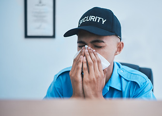 Image showing Man, blowing nose and working at desk in office for security, safety or surveillance control room or person with allergies or hayfever. Sick, guard and employee with flu, virus or tissue for sneeze