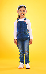 Image showing Happy, portrait and girl child for fashion in studio with confidence, smile and positive attitude. Excited, clothes and young kid with happiness, pose and casual style isolated on a yellow background