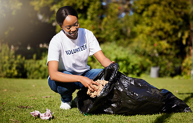 Image showing Volunteer, woman and cleaning waste in park for community service, pollution and climate change or earth day project. African person volunteering in garden, nature or outdoor and plastic bag or trash