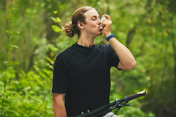 Image showing Asthma, fitness and man cyclist on a bicycle in a forest with breathing medical emergency during exercise or training. Outdoor, lung support and athlete with inhaler in nature for workout or wellness