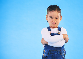 Image showing Angry, child and arms crossed with tantrum in studio with mockup space. Kid, young girl and frustrated with cross frown and pout with a problem and mad attitude with blue background and grumpy