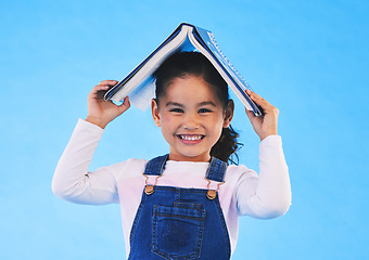 Image showing School, head and portrait of kid with book for knowledge or learning isolated in a studio blue background. Clever, smart and young girl child with notebook happy for education, story or reading