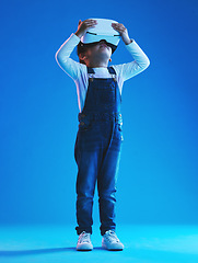 Image showing Glasses, virtual reality and metaverse with girl, futuristic and digital transformation on a blue studio background. Kid, person and model with vr headset for video games, future or augmented reality