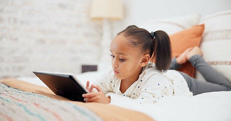 Image showing Digital tablet, relax and child on the bed playing an online game or watching a video on the internet. Technology, rest and young girl kid networking on social media or mobile app in bedroom at home.