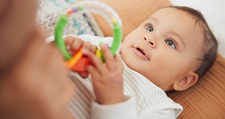 Image showing Sweet, playing and cute baby with a toy on a blanket for child development, fun and entertainment. Happy, adorable and playful infant child relaxing on a bed in his nursery or bedroom at family home.