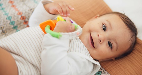 Image showing Cute, playing and sweet baby with a toy on a blanket for child development, fun and entertainment. Happy, sweet and portrait of a playful infant child relaxing on a bed in his nursery or bedroom.