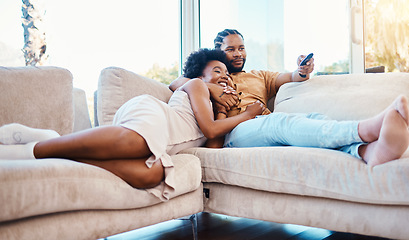 Image showing Couple, watching tv and relax on home sofa together with love, care and happiness. African man and woman in a living room with a remote control for streaming movies, show or series on a couch