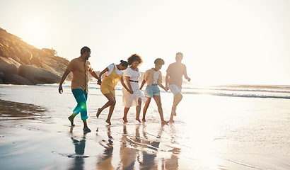 Image showing Summer, holding hands and sunset with friends at beach for freedom, support and travel. Wellness, energy and happy with group of people walking by the sea for peace, adventure and vacation together