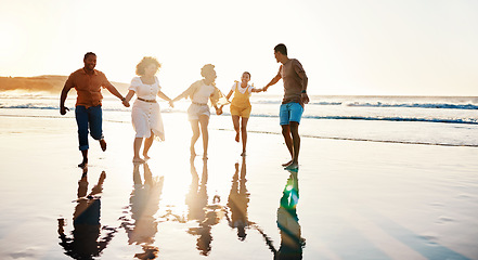 Image showing Friends, running and people happy at sunset beach for fun, freedom and travel with care. Diversity, men and women group holding hands in nature with sand, love and happiness on a vacation or holiday