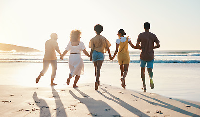 Image showing Friends, holding hands and running at sunset on beach in summer, vacation or walking together on holiday break with freedom. Group, silhouette and people with connection and support in community