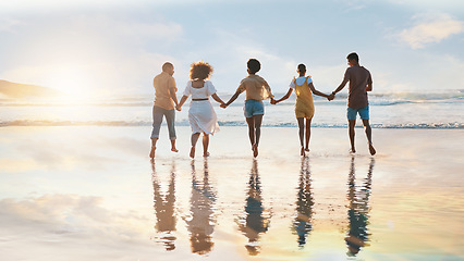 Image showing Friends, together and holding hands on beach at sunset in summer, vacation or walking on holiday break with support. Group, silhouette and people with connection, respect and kindness in community