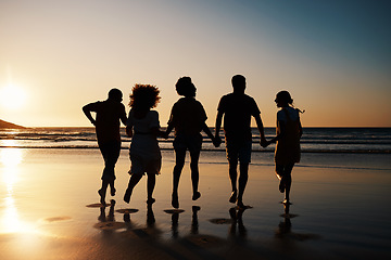 Image showing Beach, sunset and back of friends holding hands with freedom, bond and fun on summer vacation. Ocean, silhouette and rear view of people together at the sea for travel, holiday or adventure in Miami