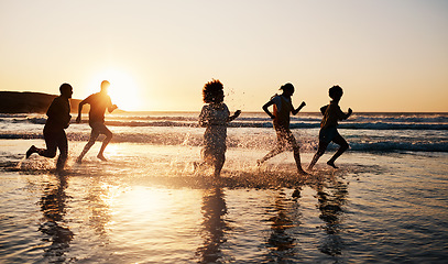 Image showing Sunrise, beach and friends with freedom, running and having fun in water together on summer vacation. Ocean, silhouette and group of people at the sea for holiday, bond and travel celebration in Bali