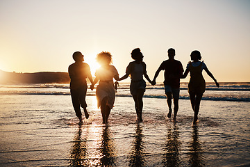 Image showing Holding hands, silhouette and friends at the beach with freedom, fun and bonding at sunset. Ocean, shadow and group of people at the sea for travel, adventure and journey in sea trip in Los Angeles