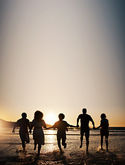 Image showing Sunset, water splash and friends holding hands at a beach with freedom, running or fun on summer vacation. Ocean, silhouette and people shadow in solidarity at the sea for travel, bond or celebration