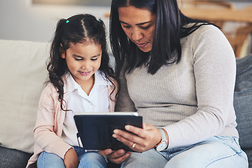Image showing Tablet, education and a mother on the sofa with her daughter in the living room of their home together. School, family or children with a mother and girl looking at an online homework assignment