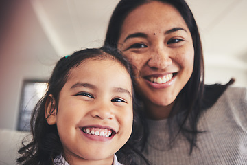 Image showing Selfie, smile and portrait of a girl with her mother bonding in the living room of their home. Happy, love and face headshot of Asian child taking a picture with her young mom at their family house.