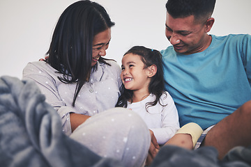 Image showing Family, morning and child in bed at home with parents, love and happiness or support. A happy woman, man and girl kid laugh together in a bedroom for fun time, playing and care or relax in a house