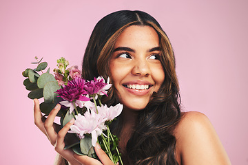 Image showing Woman, flowers and bouquet in studio for skincare, cosmetics and natural aesthetic on pink background. Face, happy model and thinking of eco beauty with floral plants, sustainability and dermatology