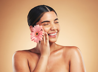 Image showing Skincare, smile and woman with flower in studio for beauty, wellness and organic cosmetics on brown background. Floral, dermatology and hand on face of model happy with plant, cosmetology or results