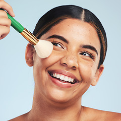 Image showing Face, happy woman and brush for makeup in studio to apply foundation for glow on blue background. Model, smile and aesthetic cosmetics for skincare tools, facial beauty powder or thinking of makeover