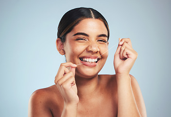 Image showing Woman, portrait and smile to floss teeth in studio for dental hygiene, care and gum gingivitis on blue background. Happy model cleaning mouth with oral thread for fresh breath, healthy habit or tooth