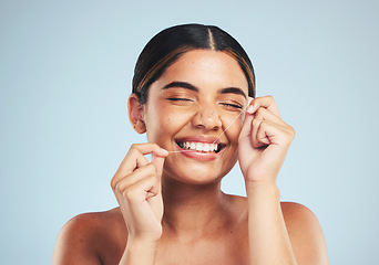Image showing Woman, smile and floss teeth in studio for dental hygiene, care and gum gingivitis on blue background. Happy female model cleaning mouth with oral thread for fresh breath, healthy habit and grooming