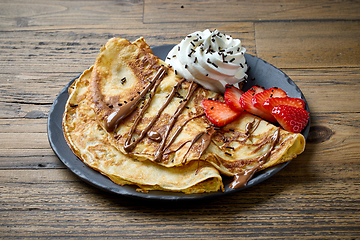 Image showing plate of crepes on wooden table