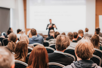 Image showing Speaker giving a talk in conference hall at business event. Rear view of unrecognizable people in audience at the conference hall. Business and entrepreneurship concept.