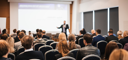 Image showing Speaker giving a talk in conference hall at business event. Rear view of unrecognizable people in audience at the conference hall. Business and entrepreneurship concept.