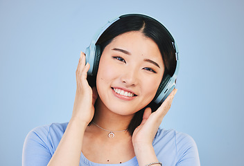 Image showing Portrait of happy Asian woman in studio with headphones for streaming radio, subscription and relax. Sound, podcast and face of person listening to music, audio and track for calm on blue background