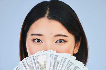 Image showing Money, beauty and woman cover face on blue background for winning, cash fan or financial prize. Lottery, portrait and asian person or winner with bonus, cosmetics secret or finance profit in studio